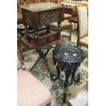 An ebonised wood plant stand, the circular top on three elephant mask supports, 35cm diameter,