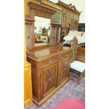 A late-Victorian carved oak sideboard, the mirrored back above two drawers and two cupboard doors,