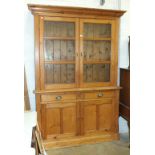 A late-19th century stripped pine dresser, the cornice above a pair  of glazed doors, two drawers