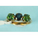 A three stone ring claw set a round cut sapphire between two round cut peridots in unmarked gold