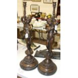 A pair of bronzed metal candle holders in the form of winged cherubs holding torches, 70cm high.