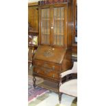 A 1950's oak bureau/bookcase, the upper shelved section fitted with a pair of leaded-light doors