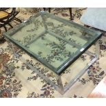 A modern glass and metal coffee table, the chrome rectangular frame supporting a glass plate,