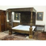 A good quality reproduction oak four-poster bed having a pair of heavily-carved posts, canopy,