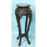 A Chinese carved hardwood urn stand, the top inset with pink marble, raised on prunus-carved