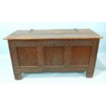 An antique oak coffer, the hinged lid above a carved panel front, 144cm wide, 74cm high.