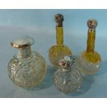 A pair of tall cut glass scent bottles with silver screw lids, 16cm high and two other silver topped