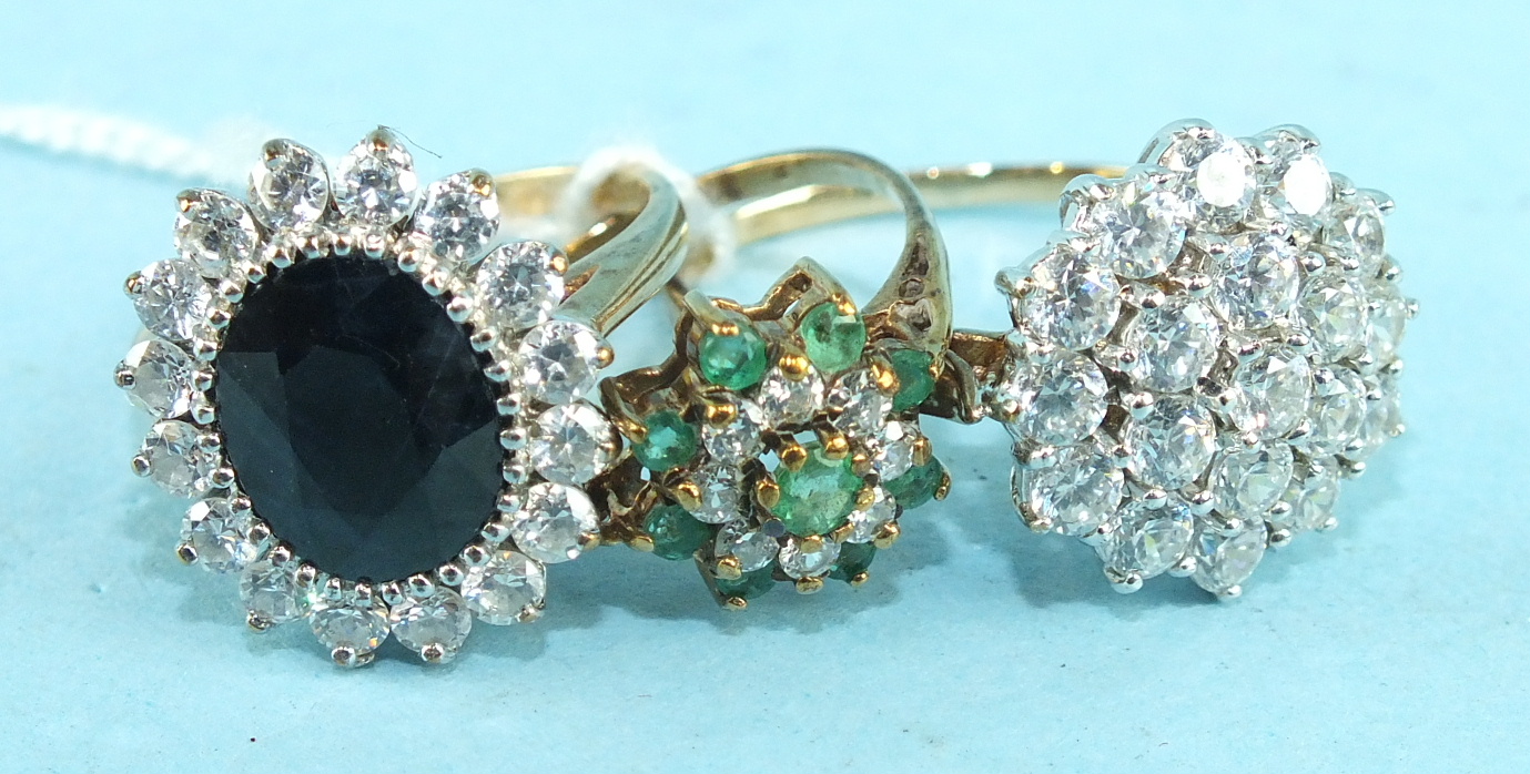 An emerald and synthetic white stone cluster ring in 9ct gold mount and two other synthetic stone