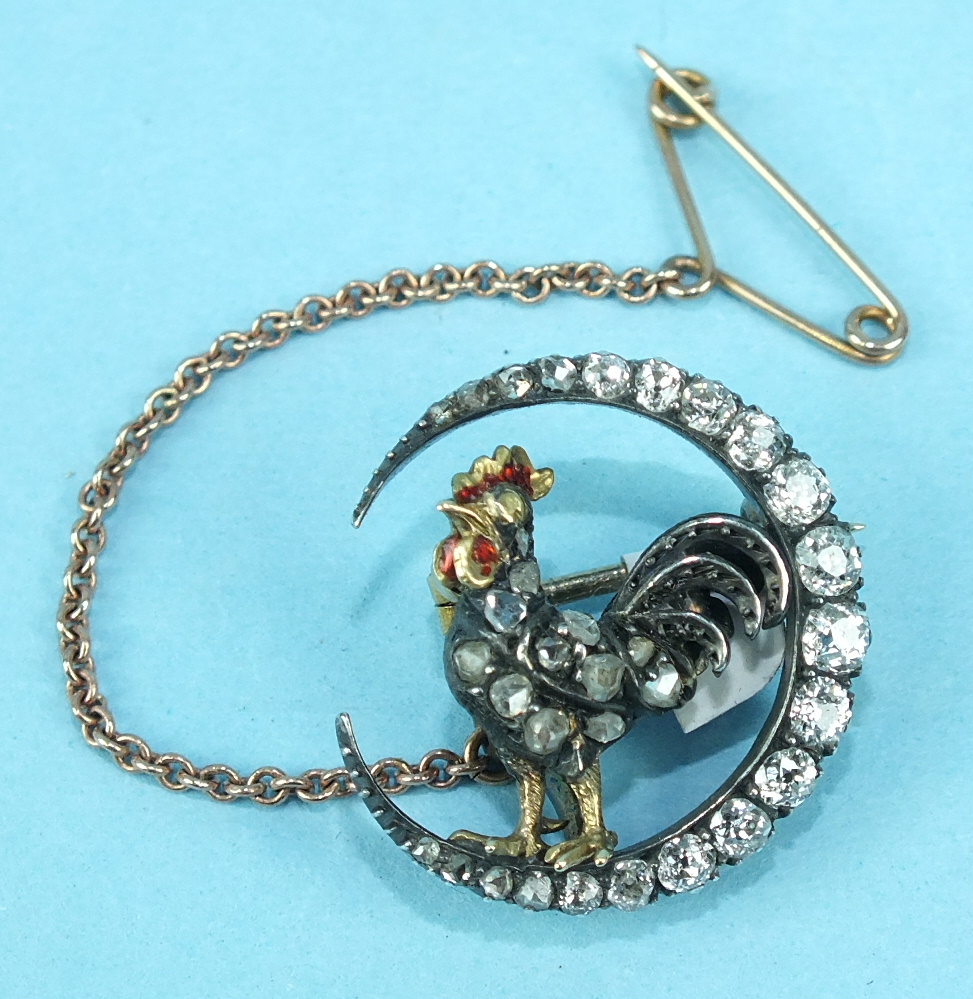 A Victorian diamond brooch in the form of a cockerel within a crescent moon, the silver cockerel set