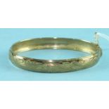 A 9ct gold hinged bangle with engraved decoration, 6.5cm across, 7.6g.