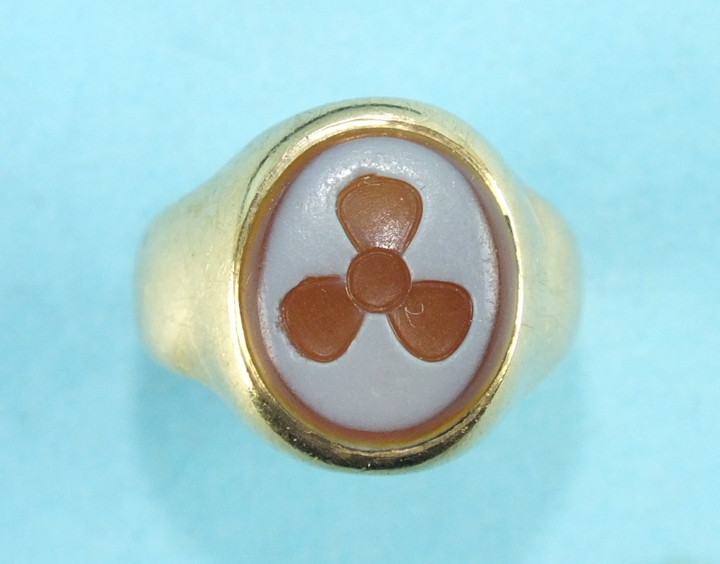 An 18ct gold signet ring set a hard stone cameo with propeller motif, size L, 4.9g.
