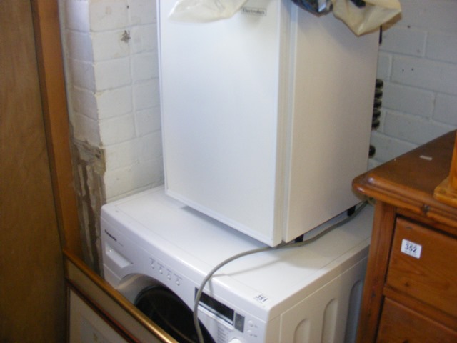 A panasonic washing machine together with a mini electrolux fridge