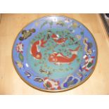 A large cloisonne enamel charger plate decorated with fish on a green central background blue rim