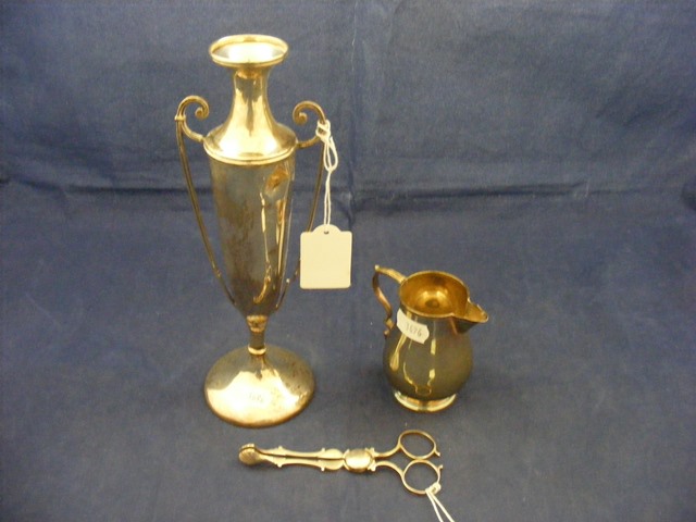 A pair of silver sugar nips together with a silver cream jug and urn