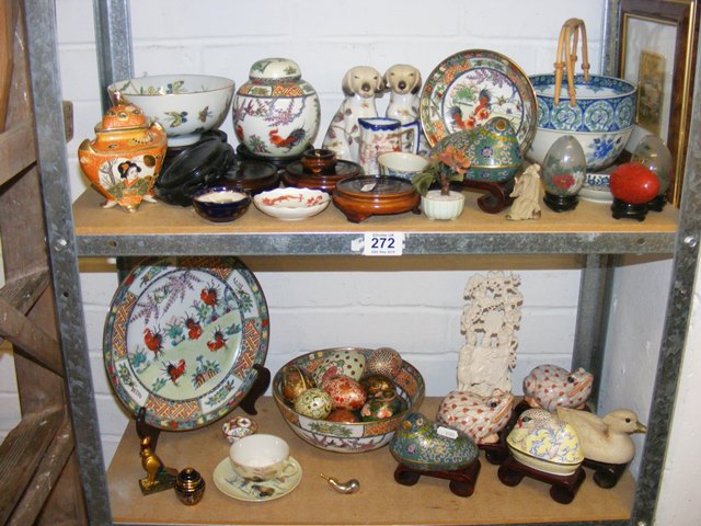 A large quantity of oriental ornaments on two shelves to include cloisonne birds, eggs,