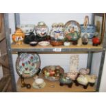 A large quantity of oriental ornaments on two shelves to include cloisonne birds, eggs,