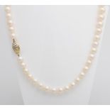 Perlkette in Cremetönen mit ovaler GG-Schließe besetzt mit drei Diamanten (ein Stein fehlt).