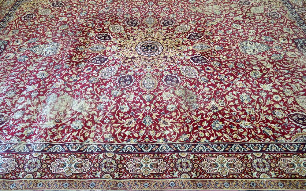 Large Persian red ground carpet with central shaped medallion and floral motifs, with multiple