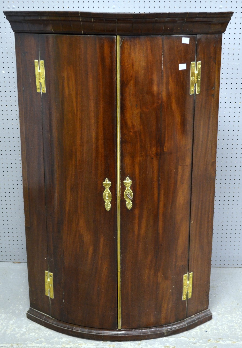 19th century mahogany wall hanging bowfronted corner cupboard, the two doors revealing shelves
