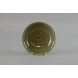 Chinese celadon glazed saucer with central moulded leaf decoration on round foot, 15cm diameter,