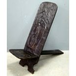 Carved African chair of X-frame proportion, carved with a Native figure with an Axe