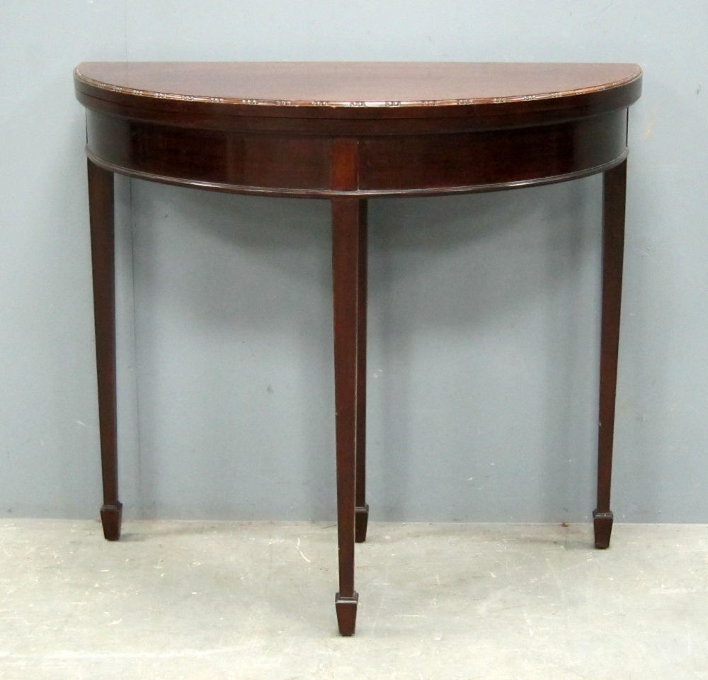 Mahogany demi lune card table, on square tapering legs to spade feet