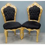 A pair of French style high back gilt salon chairs, with foliate top rails, black button back