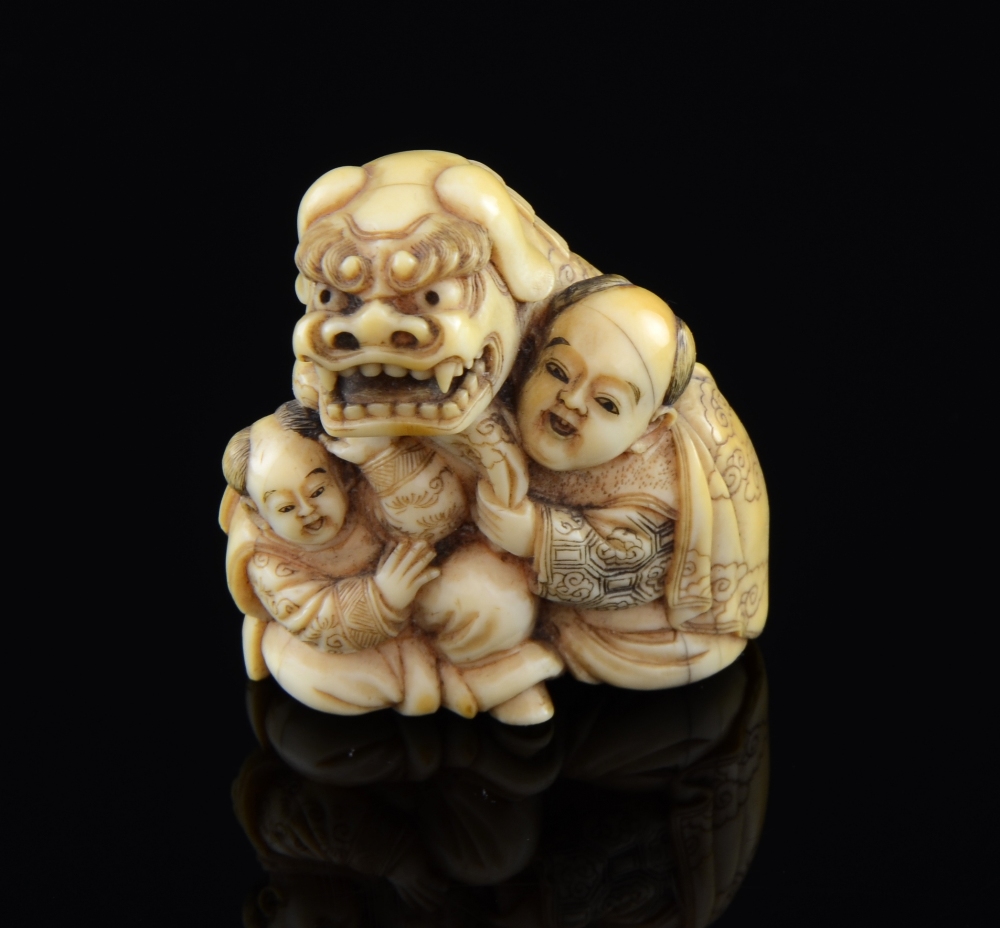 Carved Ivory Netsuke of 'The Lion festival Dog' with two attendants signedGood condition overall