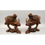 A pair of carved hardwood water buffalo each with figure seated on the back 19cm high