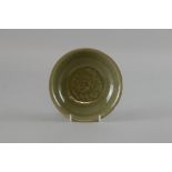 Chinese celadon glazed saucer with central moulded leaf decoration on round foot, 15cm diameter,