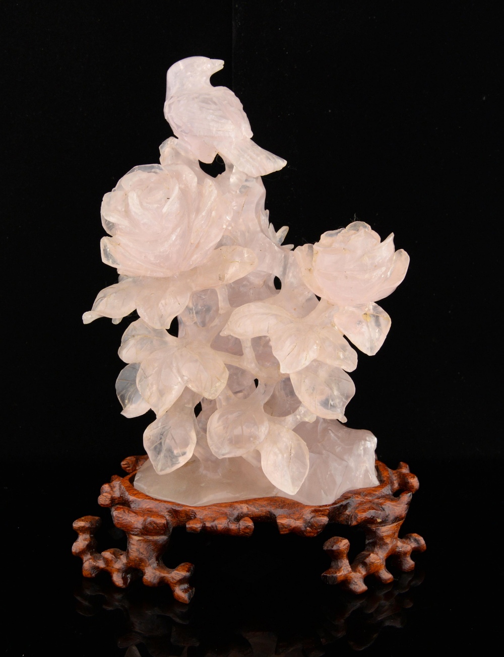 Chinese rose quartz carving of a bird amongst flowers and foliage, on hardwood base, 20cm high,