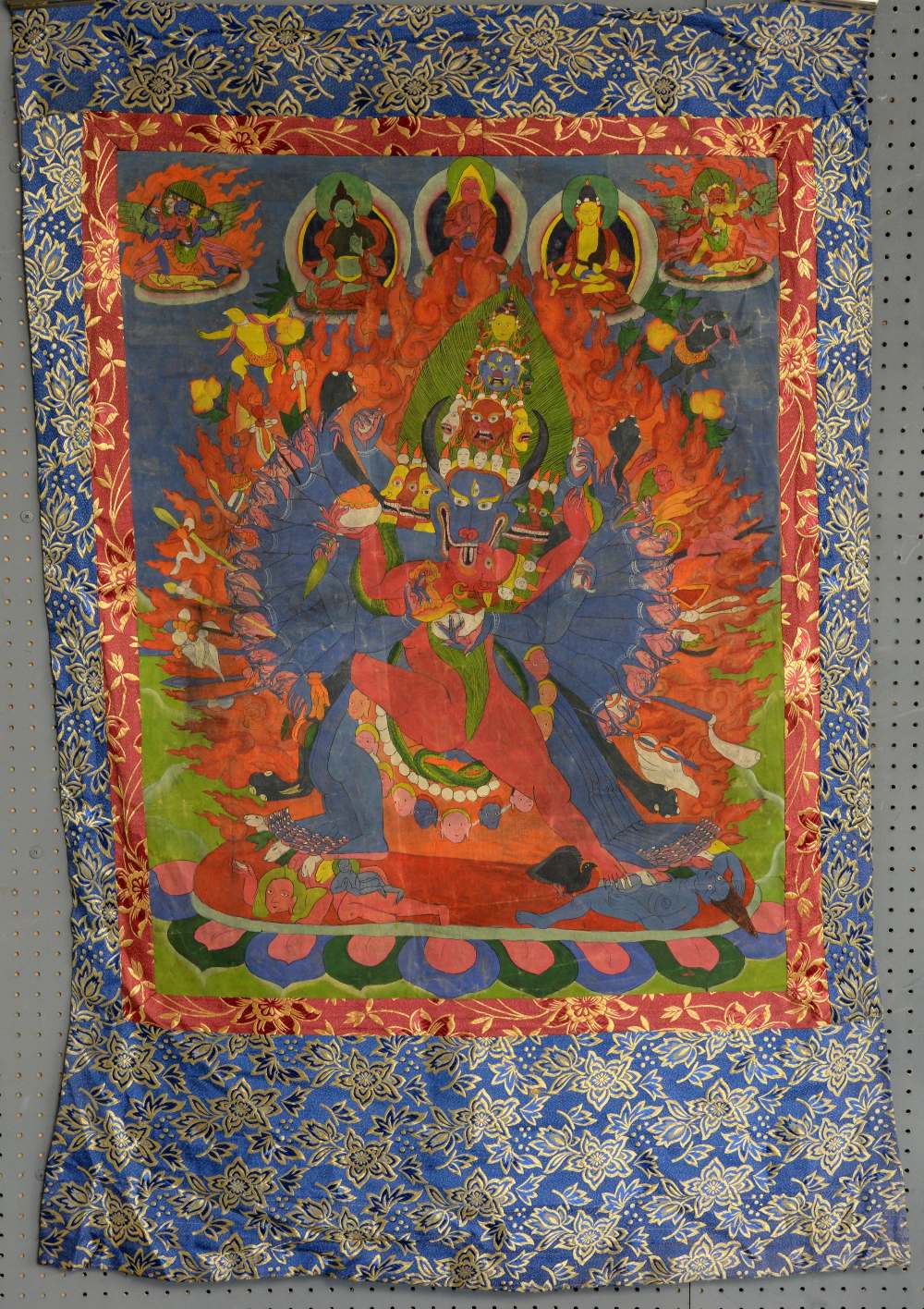 Tibetan Thangka painting depicting a many armed and legged figure with horned animals head being