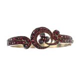 A late 19th century garnet and red paste bangle and bracelet, the hinged bangle with central