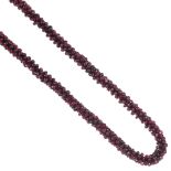 A garnet necklace, designed as a continuous woven strand of garnet beads. Length 65cms.