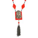 An Egyptian style necklace, the metal death mask on a red plastic panel suspending a tassle, to