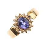 A tanzanite and diamond cluster ring. The oval-shape tanzanite, within a brilliant-cut diamond