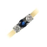 An 18ct gold diamond and sapphire three-stone ring. The circular-shape sapphire, with brilliant-