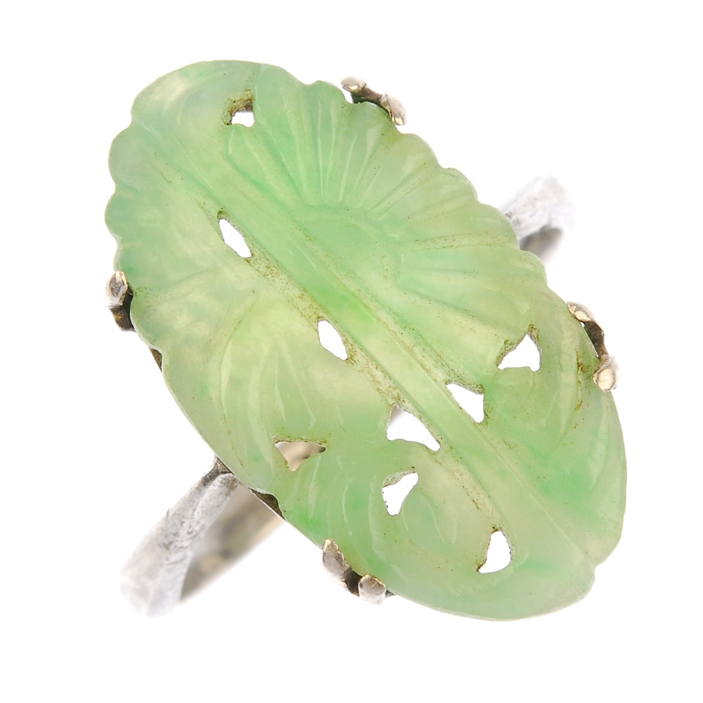 A jade ring. The carved oval jadeite panel, of foliate and openwork design, to the tapered shoulders