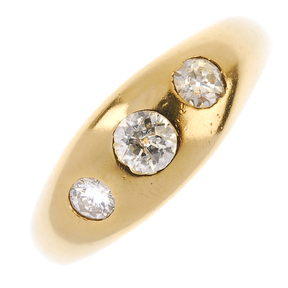 An early 20th century 18ct gold diamond three-stone ring. The graduated old-cut diamond line,