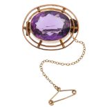 An early 20th century 9ct gold amethyst brooch. The oval-shape amethyst collet, within a double