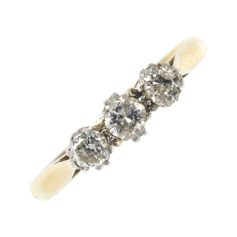 A mid 20th century 18ct gold and platinum diamond three-stone ring. The circular-cut diamonds, to