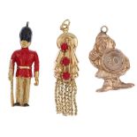 A selection of thirteen charms. To include a 9ct gold black and red enamel Queens Guard charm, a