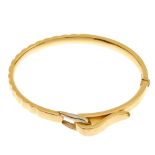 A hinged bangle. Designed as a bi-colour buckle, to the hinged bangle with groove detail. Inner