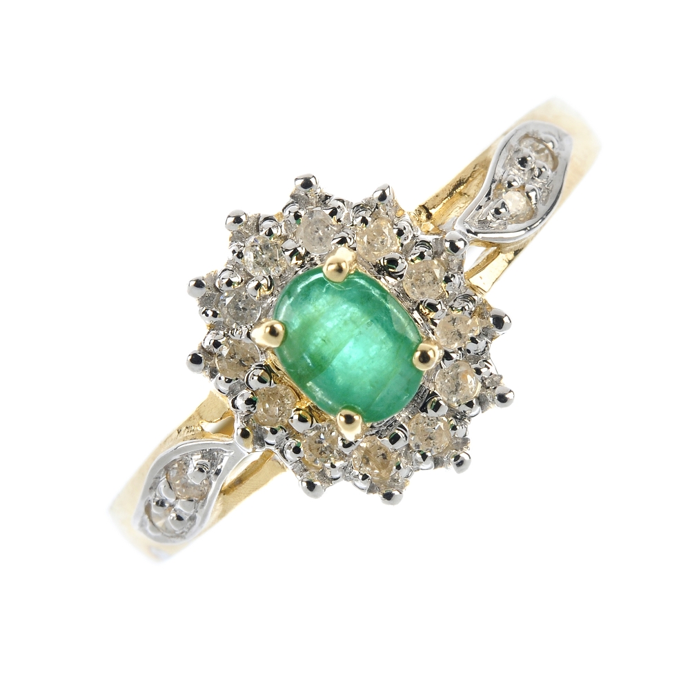 A 9ct gold emerald and diamond cluster ring. The oval-shape emerald, within a brilliant-cut