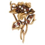 A 1950s 9ct gold garnet and seed pearl floral brooch. The circular-shape garnet and seed pearl