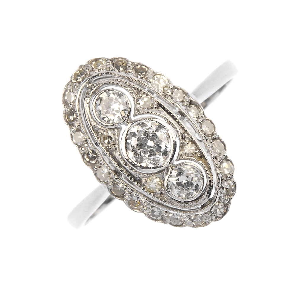 A diamond panel ring. Of oval outline, the three graduated circular-cut diamonds, within a single-