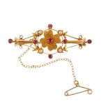 An early 20th century 15ct gold ruby and split pearl brooch. The circular-shape ruby and textured
