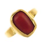 A coral ring. The oval coral cabochon collet, to the plain band. Weight 8gms. Coral untested.