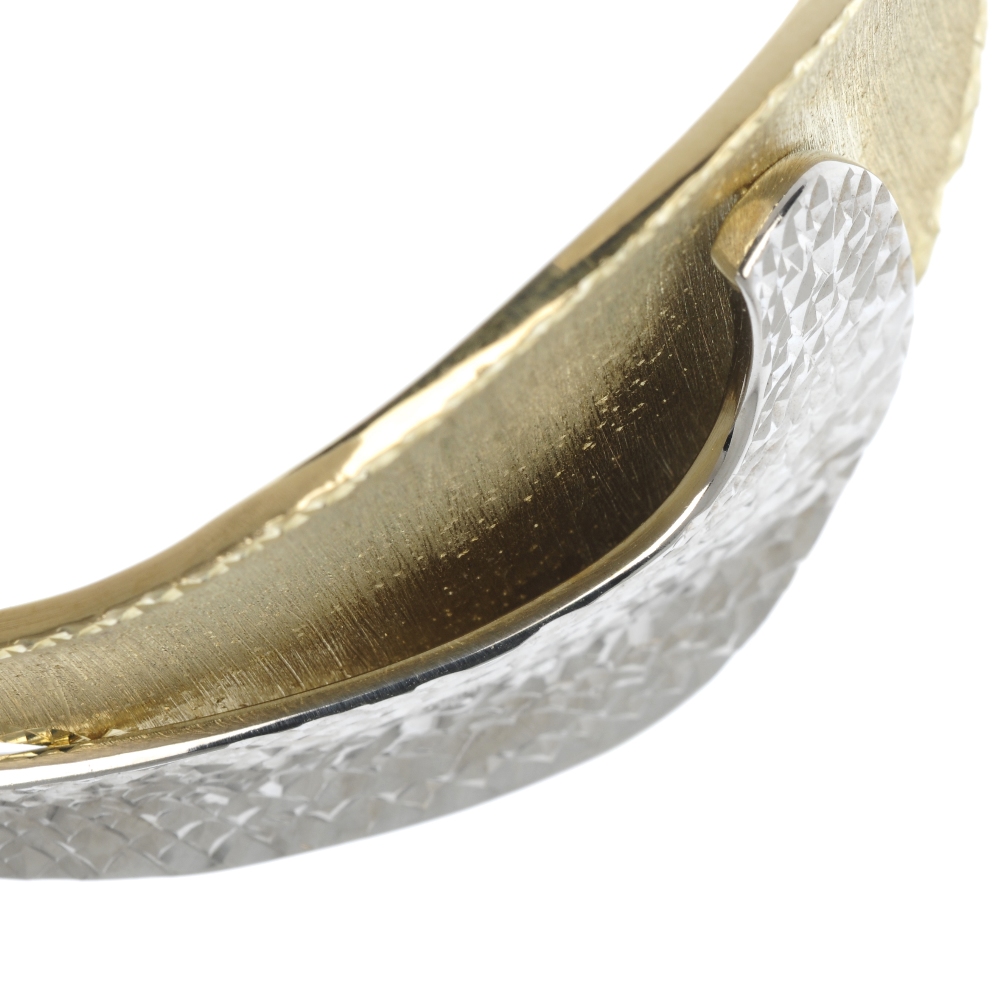 A 9ct gold bi-colour hinged bangle. The textured curved panels, to the tapered half-bangle. - Image 2 of 2