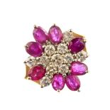 A 9ct gold ruby and diamond cluster ring. The brilliant-cut diamond cluster, within an oval-shape
